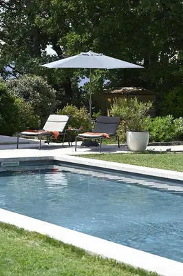 a swimming pool with two chairs and an umbrella at Les Agapanthes de Gordes in Gordes