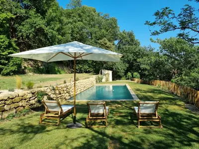 two chairs and an umbrella next to a swimming pool at Magnifique Mas Provençal in Lauris