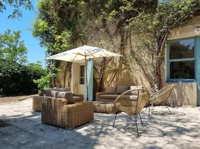 a patio with wicker chairs and an umbrella at Magnifique Mas Provençal in Lauris