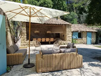 a patio with two couches and an umbrella at Magnifique Mas Provençal in Lauris