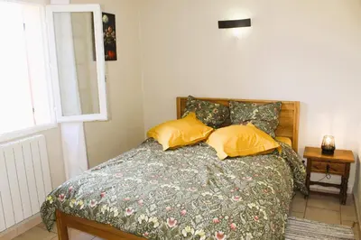 a bedroom with a bed with yellow pillows and a window at Mas La Gentille ,,, à la campagne , beautiful outdoor , swimming pool , pool house , Nice green Garden , BBQ ,,, only for you , pour passer un séjour inoubliable in Pernes-les-Fontaines