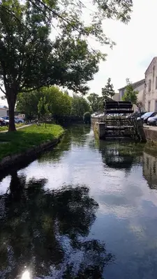 a river with a bridge and trees in a city at Casa Mia, chambre privée en Provence in LʼIsle-sur-la-Sorgue