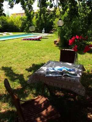 a table and chairs in a yard with a pool at L'Islo Bamboo in Saumane-de-Vaucluse