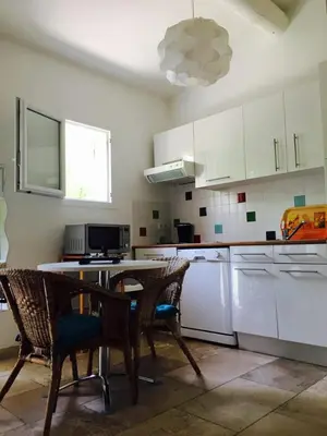 a kitchen with white cabinets and a table and chairs at L'Islo Bamboo in Saumane-de-Vaucluse