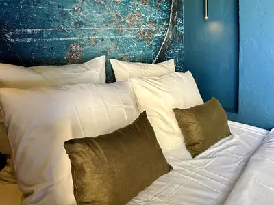 a white bed with pillows and a blue wall at LOVE IN L'ISLE/SORGUE Le crépuscule in LʼIsle-sur-la-Sorgue
