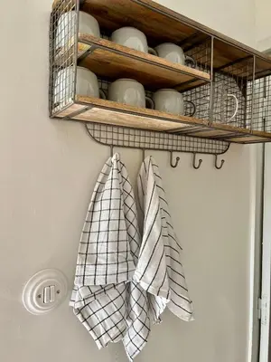 a shelf with cups and towels hanging from it at Le Cabanon de Léandre in Meyrargues