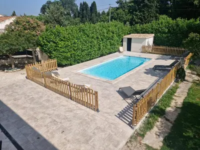 a swimming pool with a wooden fence around it at A l'ombre de l'olivier in Orgon