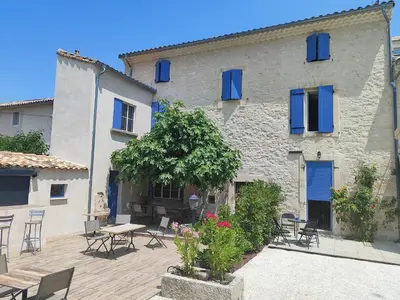 a building with blue shutters and a table and chairs at Coeur de Provences in Saint-Didier