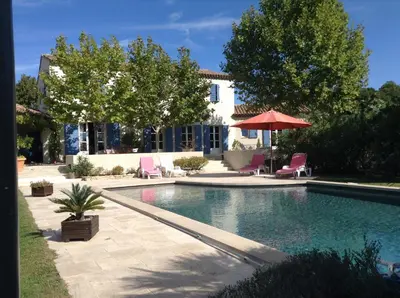 a swimming pool with two chairs and an umbrella at La bastide de Cocagne in Rognes