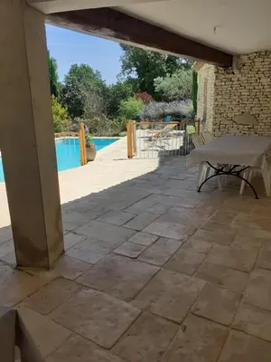 a patio with a table and a pool in the background at Goult (LUBERON) A 150 m de la piste cyclable Maison en campagne avec Gde piscine in Goult