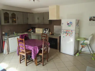 a kitchen with a table and chairs and a refrigerator at Goult (LUBERON) A 150 m de la piste cyclable Maison en campagne avec Gde piscine in Goult