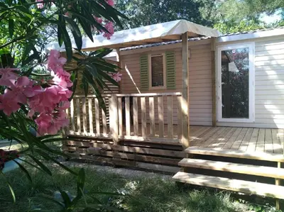 a cabin with a deck and an umbrella at Mobilhome 228 proche du Lac , Tv , clim ect Camping in La Roque-dʼAnthéron