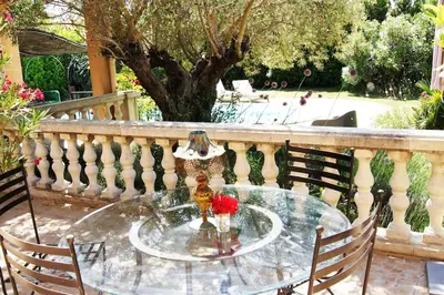 a glass table with a vase and roses on a balcony at villa entre st rémy de provence et avignon in Noves