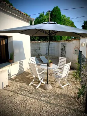 a table and chairs under an umbrella in a yard at Viva la vida in Entraigues-sur-la-Sorgue