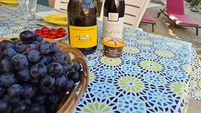 a table with two bottles of wine and a basket of grapes at Maison provençale rénovée in Pernes-les-Fontaines