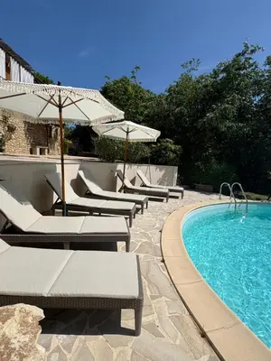 a row of chairs and umbrellas next to a swimming pool at Le Pavillon de Nina in Puget