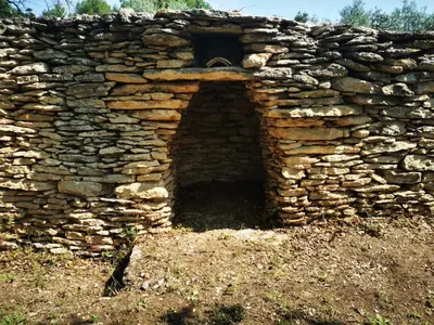 a stone building with a door in a stone wall at Le Fiacre entre chênes et oliviers dans le Luberon in Cabrières-dʼAvignon