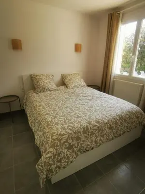 a bedroom with a bed with a comforter and a window at Le Fiacre entre chênes et oliviers dans le Luberon in Cabrières-dʼAvignon