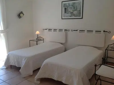 two beds in a room with white walls at Le Clos des Cigales in Roussillon