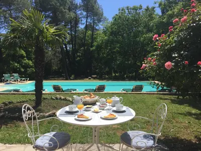 a table with food on it next to a pool at Le Clos des Cigales in Roussillon