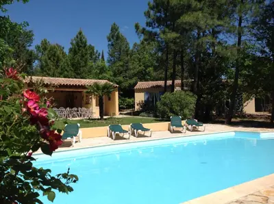 a swimming pool with chairs and a house at Le Clos des Cigales in Roussillon