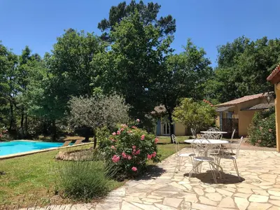 a garden with a table and chairs next to a pool at Le Clos des Cigales in Roussillon