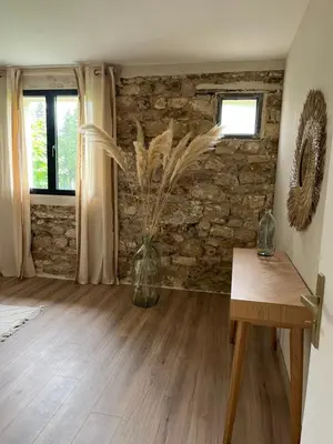 a room with a stone wall and a vase with flowers at LE MAS MILA in Monteux