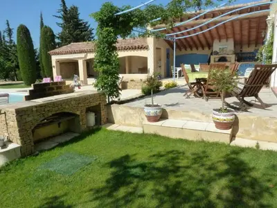 a backyard with a stone fireplace and a patio at Magnifique villa au calme avec piscine, sauna et jacuzzi in Pélissanne