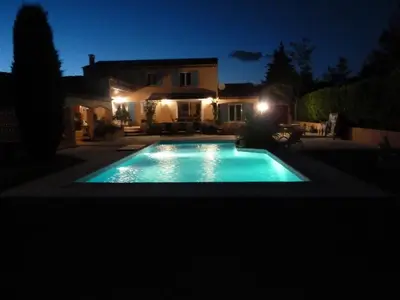 a swimming pool in front of a house at night at Magnifique villa au calme avec piscine, sauna et jacuzzi in Pélissanne