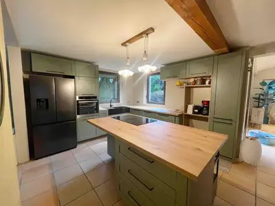 a kitchen with green cabinets and a wooden counter top at Mas de Peyre in Le Beaucet