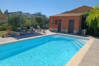 a blue swimming pool with chairs and a house at Le Cavaou in Mérindol