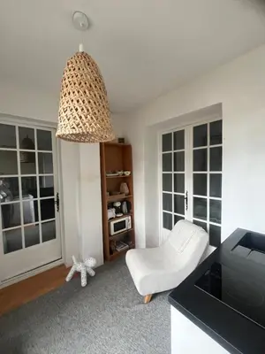 a living room with a white chair and a pendant light at Le Verger in Aix-en-Provence