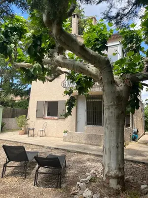 a tree and two chairs in front of a house at Le Verger in Aix-en-Provence