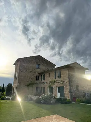 a large stone building in a field with a cloudy sky at Les Oliviers De Notre Dame in Mazan