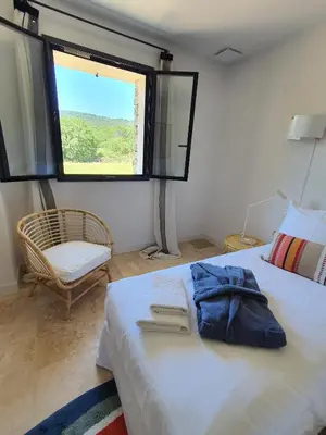 a bedroom with a bed and a window and a chair at L'Instant Luberon in Gordes