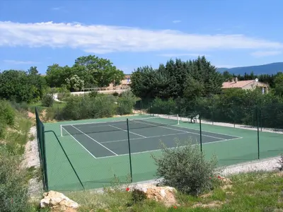 a tennis court on a hill next to a house at La Bastide de la Peyrolière avec piscine et tennis face au Luberon in Apt