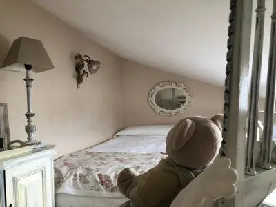 a teddy bear sitting in front of a bed at L’île aux fleurs in Ventabren