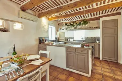 a large kitchen with a counter and a table at L’île aux fleurs in Ventabren