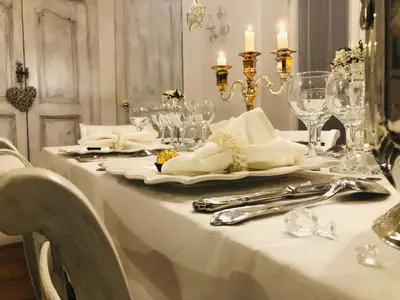 a white table with glasses and silverware on a table at L’île aux fleurs in Ventabren