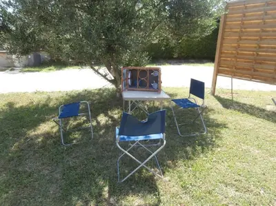 three chairs and a table with a grill in the grass at gîte à Caromb ( Mt Ventoux ) in Caromb