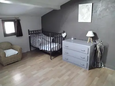 a room with a crib and a dresser and a chair at MAS LAURIE in Cheval-Blanc