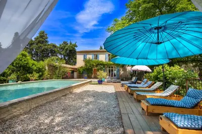 a pool with chairs and umbrellas next to a swimming pool at Mas provençal 14 personnes - parking privé in Le Thor