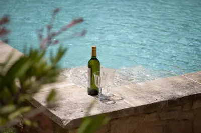a bottle of wine and a wine glass sitting on a wall at Mas provençal 14 personnes - parking privé in Le Thor