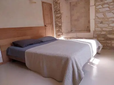 a bedroom with a bed in a room with a stone wall at Cécile - Mas de Rousseau in Eyragues