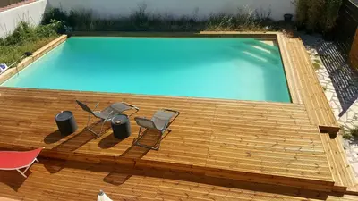 a swimming pool on a wooden deck with two chairs at STUDIO DU CHARME PROVENCAL in Sénas
