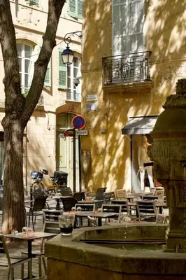 an outdoor cafe with tables and chairs and a fountain at Maison en Provence avec piscine in Éguilles