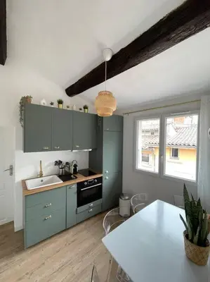 a kitchen with blue cabinets and a white table at Ravissant appartement au cœur d’Aix in Aix-en-Provence