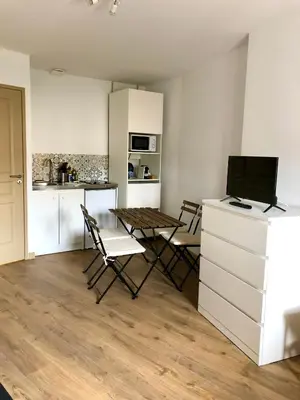 a living room with a table and chairs and a kitchen at Logement neuf, tout confort, au coeur du village in Saint-Didier