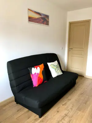 a black couch with pillows on it in a room at Logement neuf, tout confort, au coeur du village in Saint-Didier