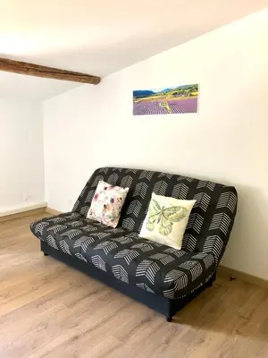 a black couch sitting in a living room at Logement neuf, tout confort, au coeur du village in Saint-Didier